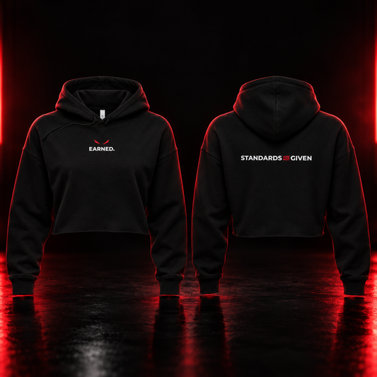 Black cropped hoodies shown from the front and back on a dark reflective studio floor with red lighting. The front hoodie has a small white 'EARNED.