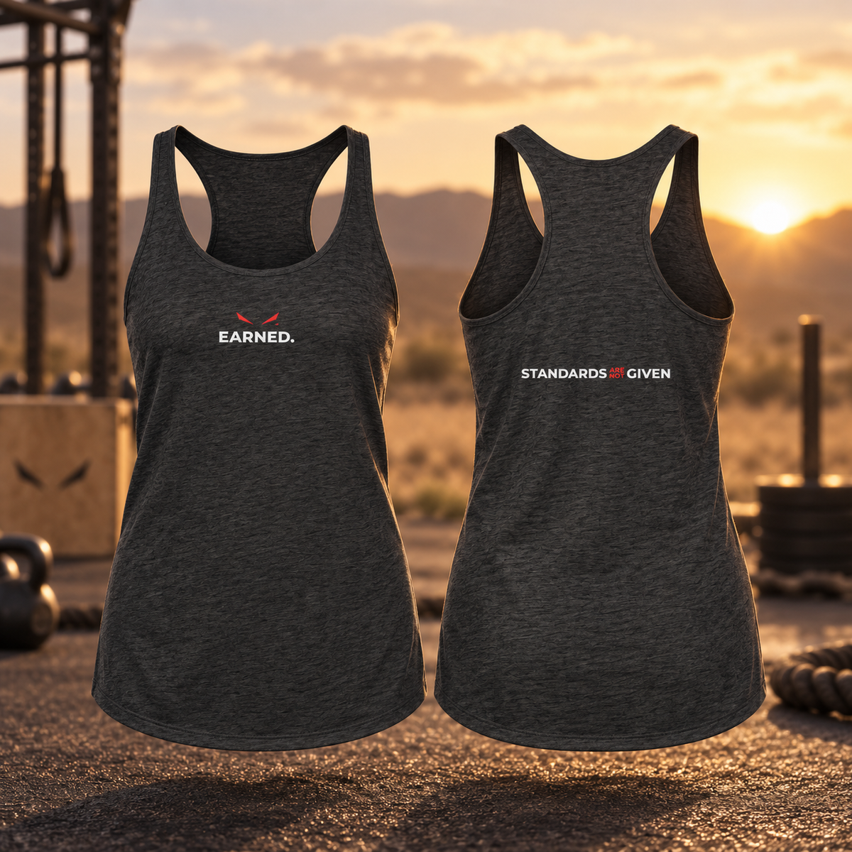 Two dark heather gray racerback tank tops shown front and back on a gym set at sunset. The front tank top has a small white 'EARNED.