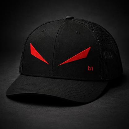 A black trucker-style baseball cap with red embroidered graphic details on the front and side, photographed against a dark studio background.